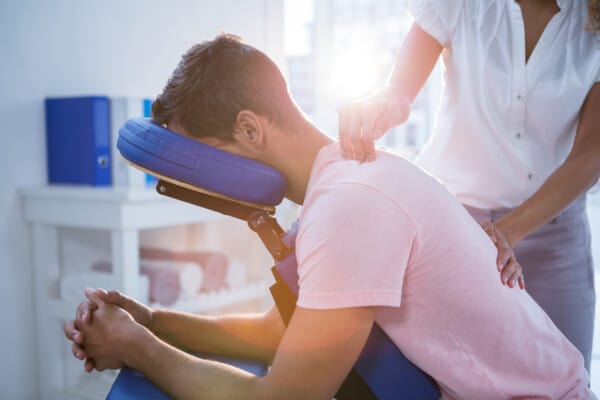 A man is receiving a relaxing massage in a massage chair to help with pain management.
